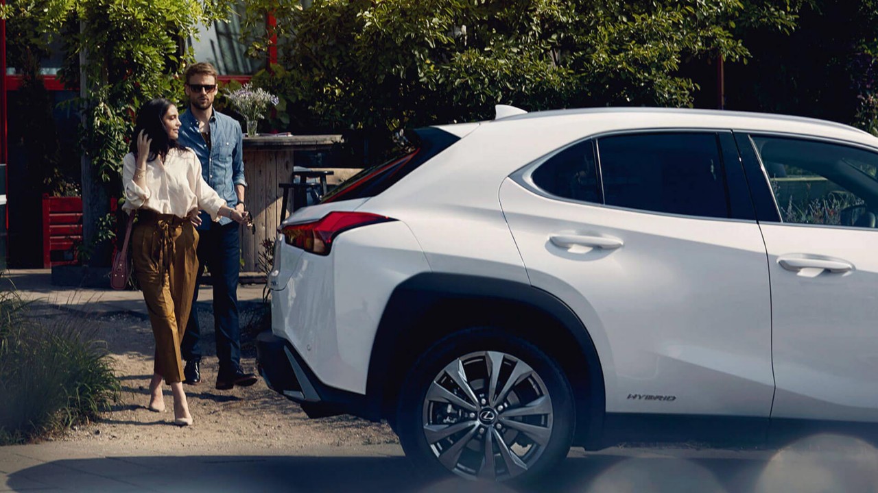 Mann und Frau am Kofferraum von weißem Lexus UX