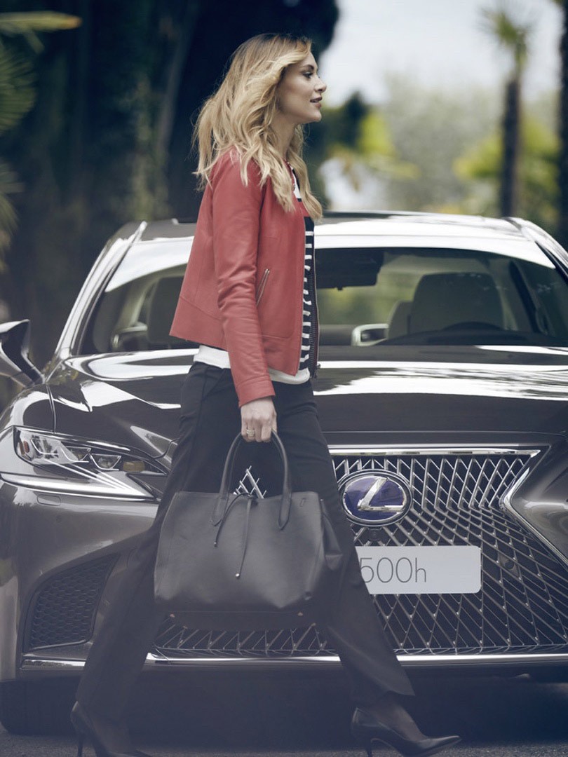 Eine Frau geht vor einem Lexus Fahrzeug 