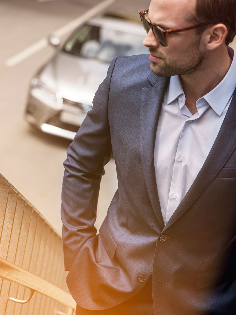 Mann mit Anzug vor einem Lexus LC