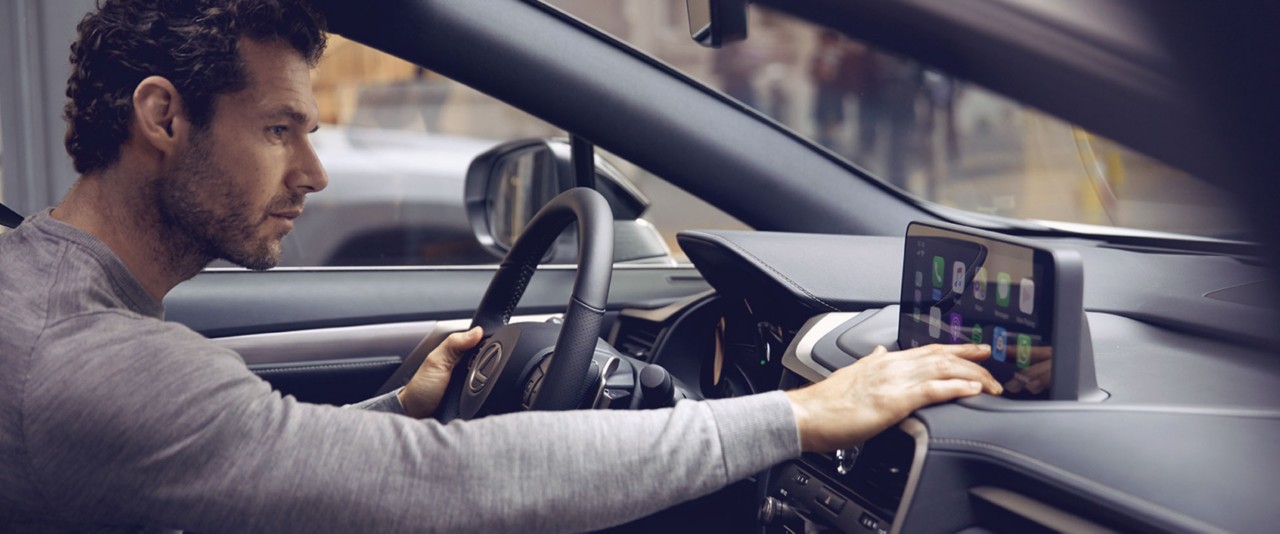 Ein Fahrer bedient das Multimedia Dashboard eines Lexus Wagens