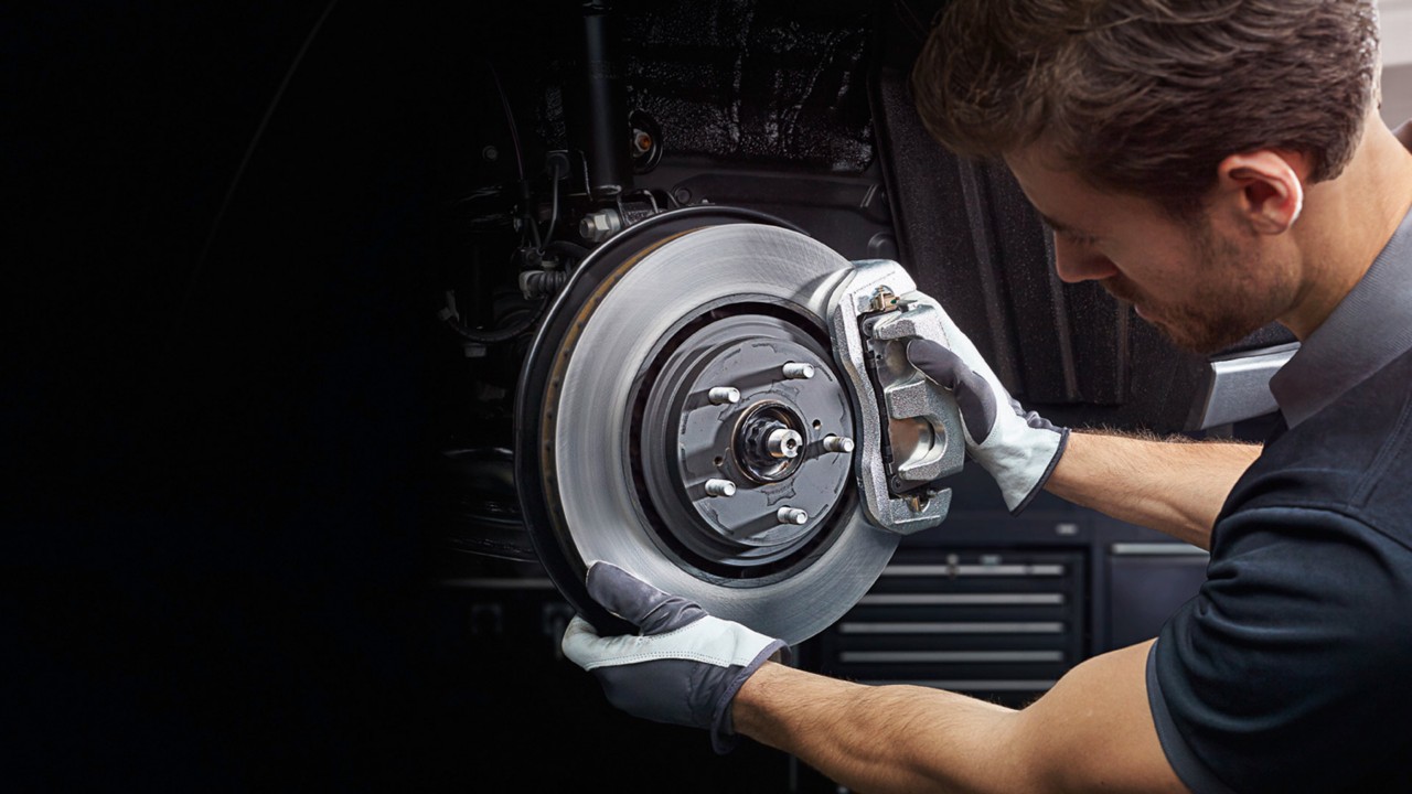Bei einem Lexus Service-Termin wird auch ein Bremsenservice gemacht (Mechaniker am Bremsklotz)