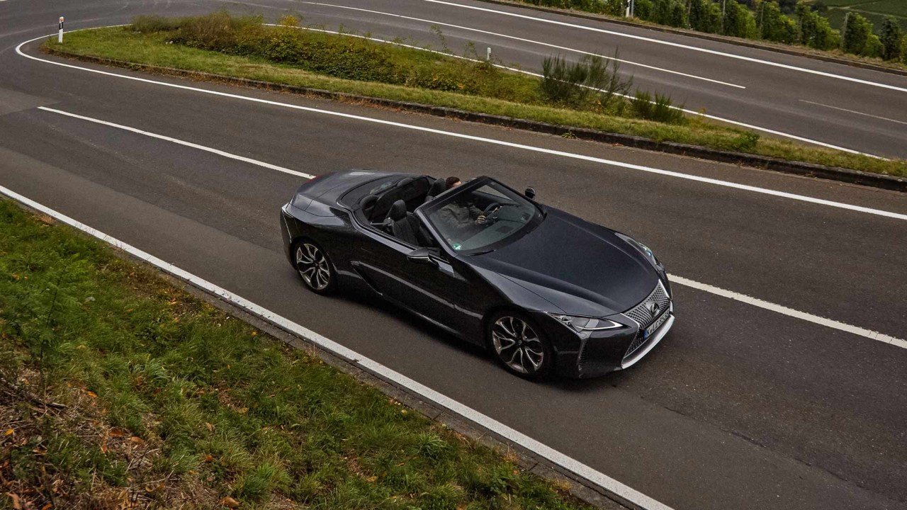 Der neue Lexus LC500 fährt auf einer schnellen Straße in grüner Umgebung.