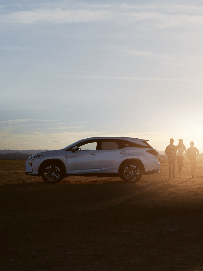 Eine Mutter steht mit ihren Kindern neben einem Lexus RX-L in der Wüste