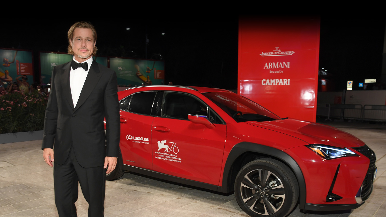 Der Darsteller Brad Pitt stehend vor einem roten Lexus UX