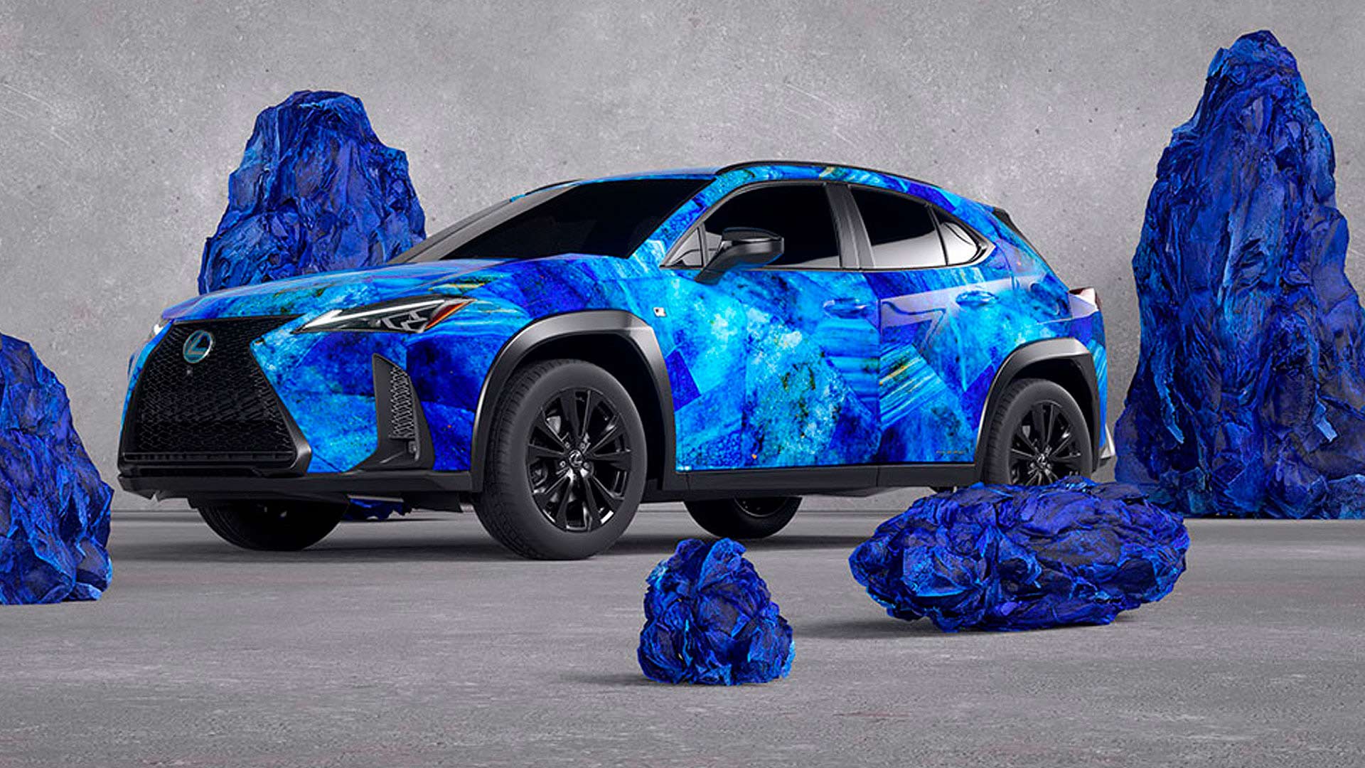 Ein Lexus mit blau bemaltem Motiv steht vor blauen Felsen.