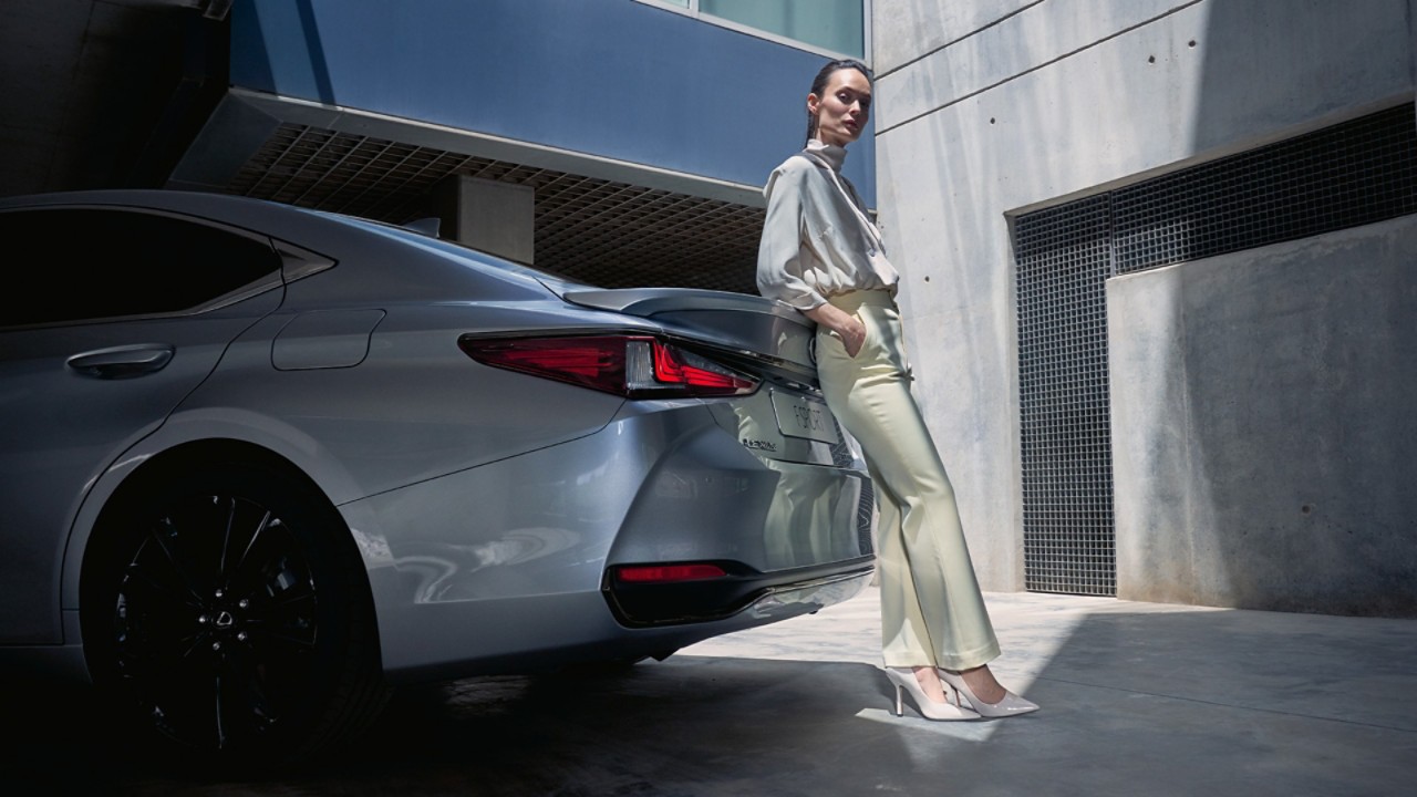 A woman leaning against a Lexus ES