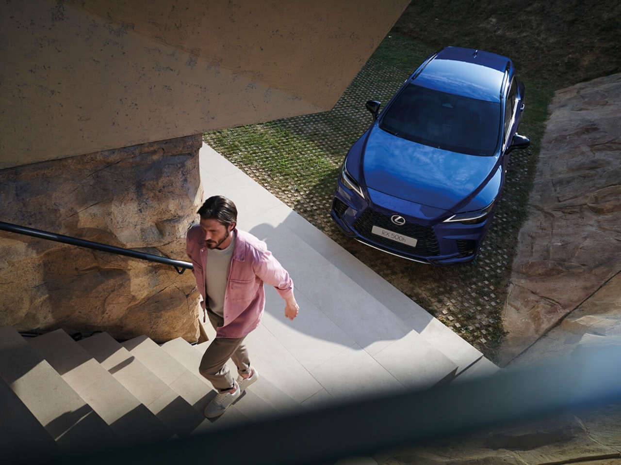 Mann nimmt die Treppe aufwärts oberhalb eines geparkten Lexus RX 500h