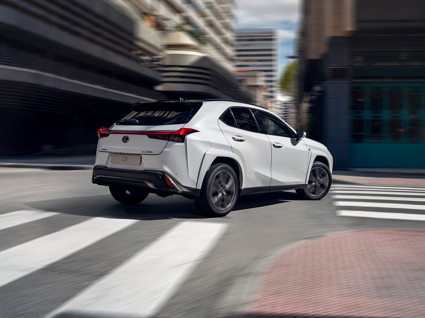 A Lexus UX driving round a corner in a town