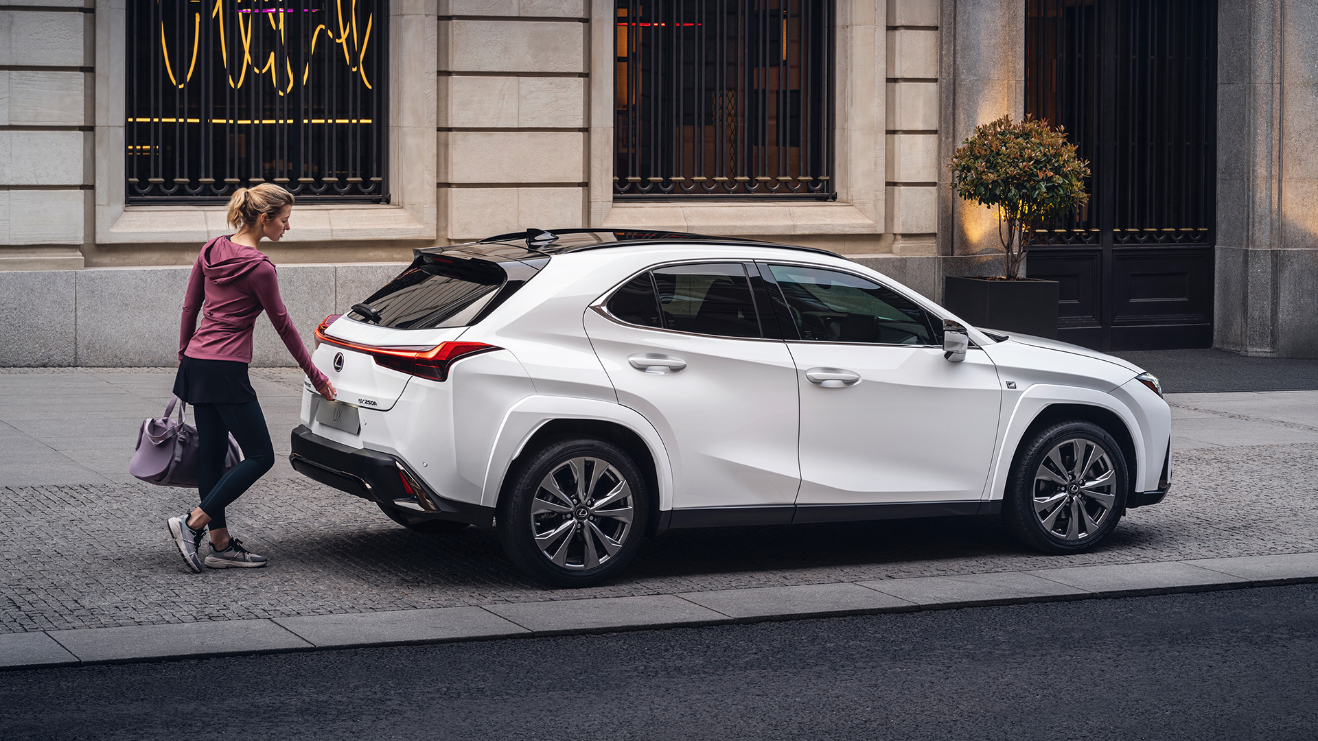 A woman opening the boot of a Lexus UX